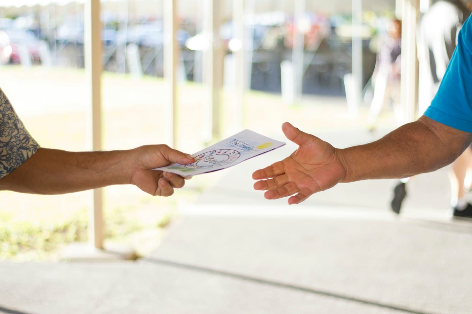 Two hands exchanging an offering envelope at a church event
