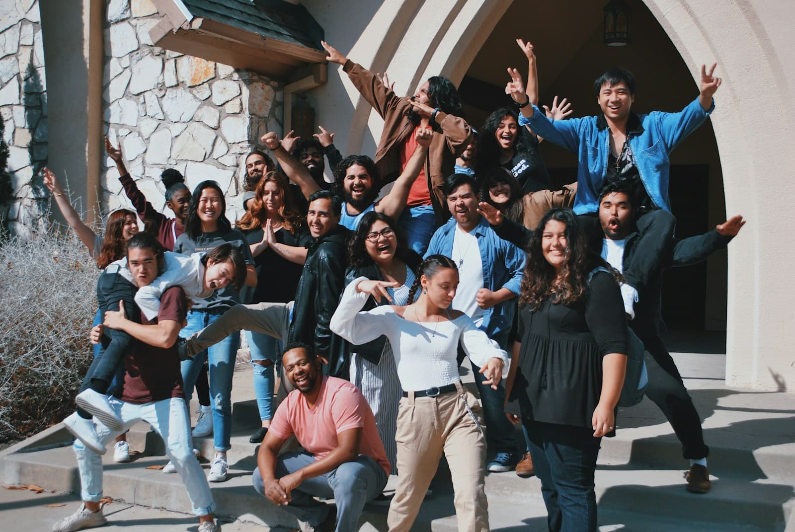 Diverse group of young people celebrating outside a small church building